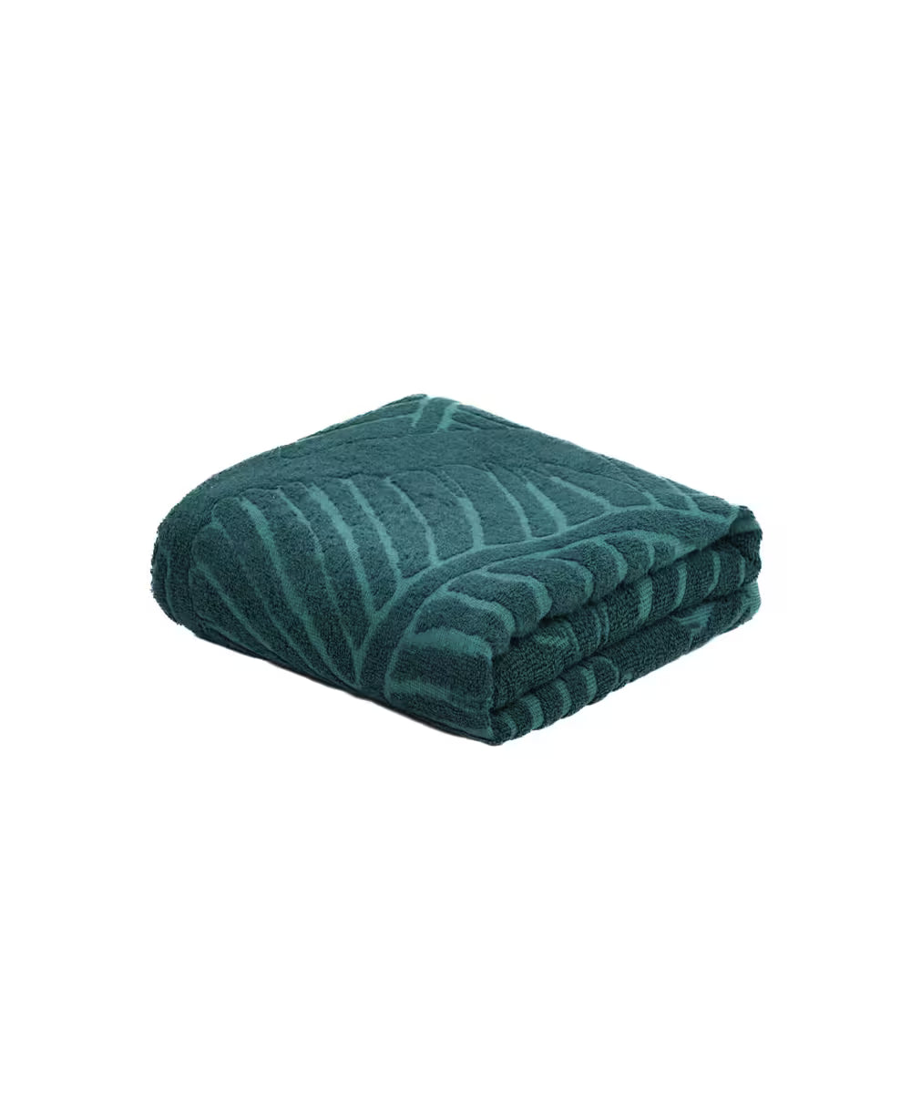 Folded teal towel with leaf pattern on a white background